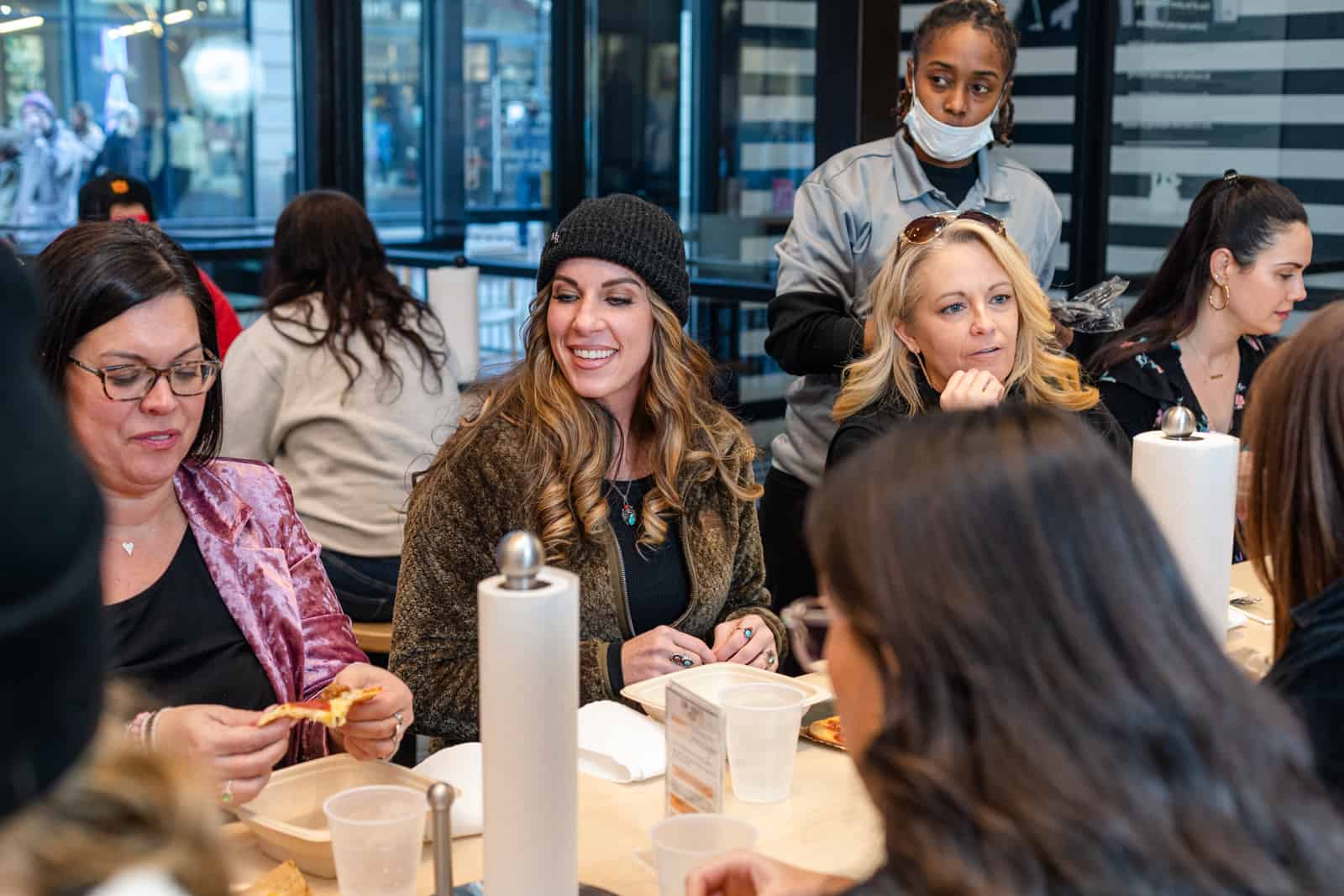 Women at restaurant laughing and eating pizza.